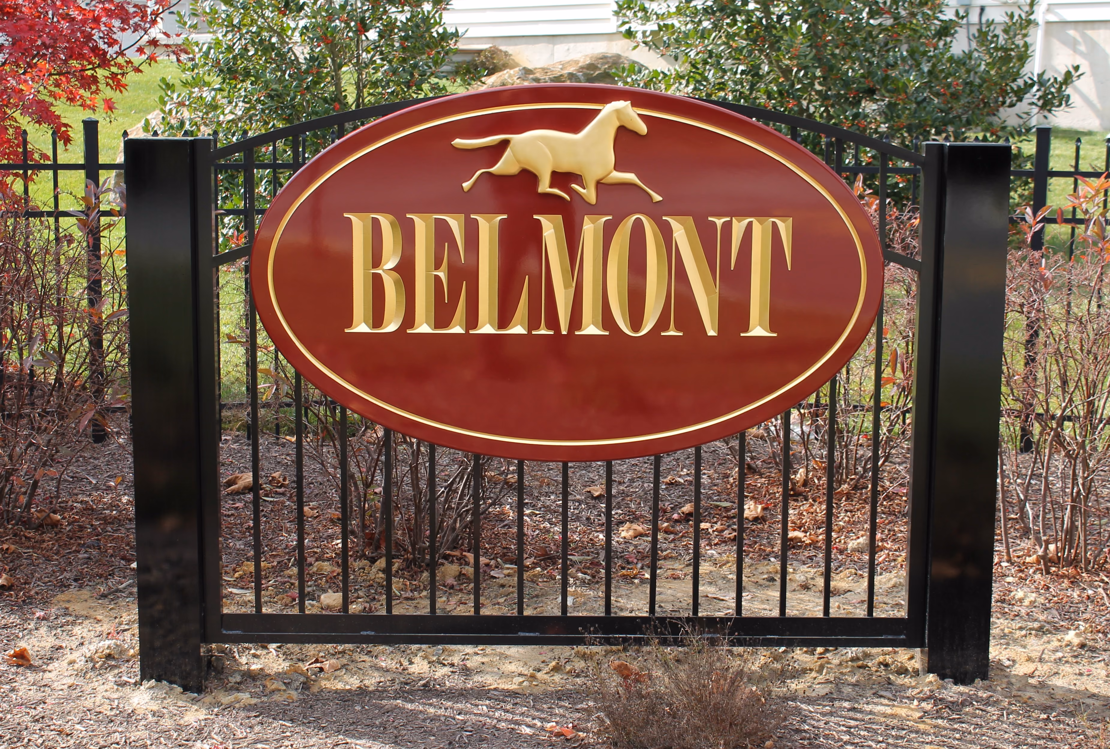 Oval, carved HDU sign mounted on a black aluminum fence