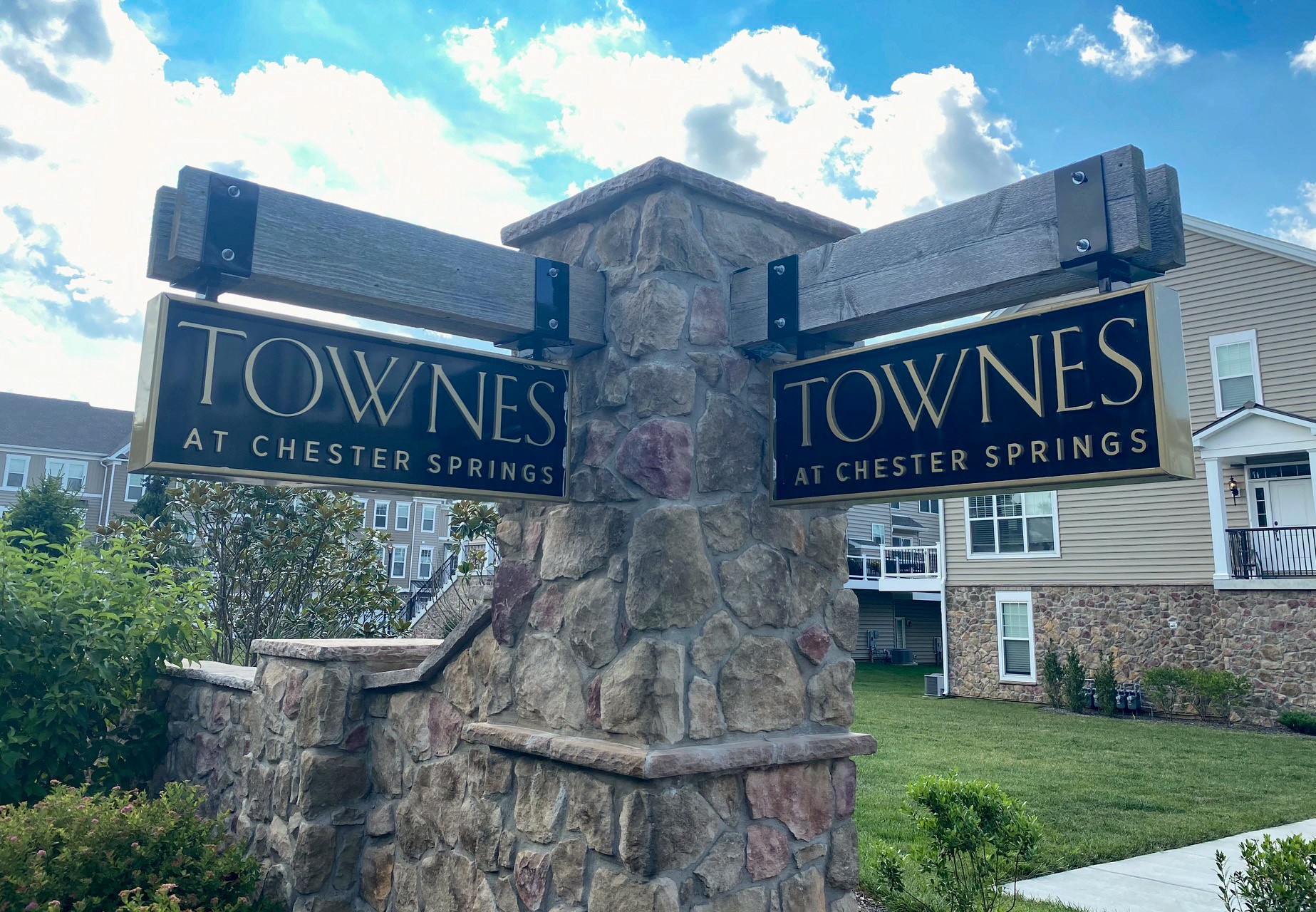 Two double-sided carved HDU signs suspended from a stone monument