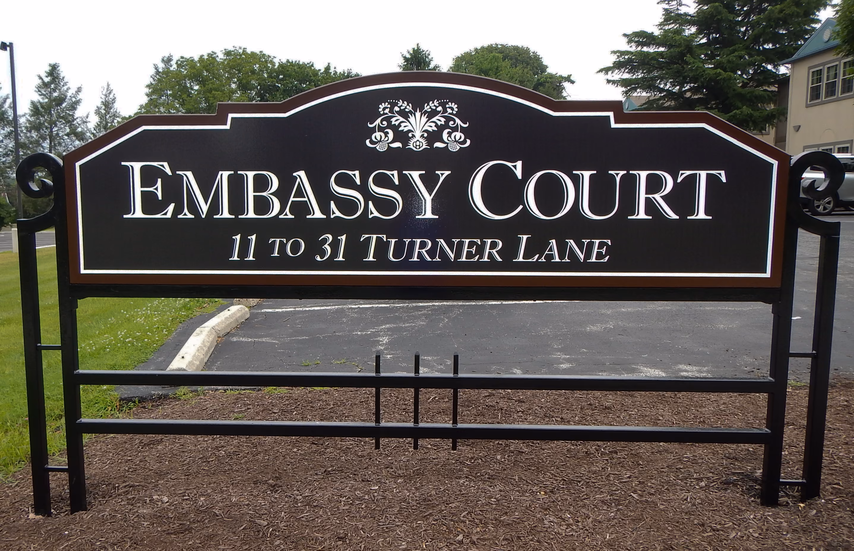Large vinyled panel mounted on ornate aluminum metalwork forming a monument sign