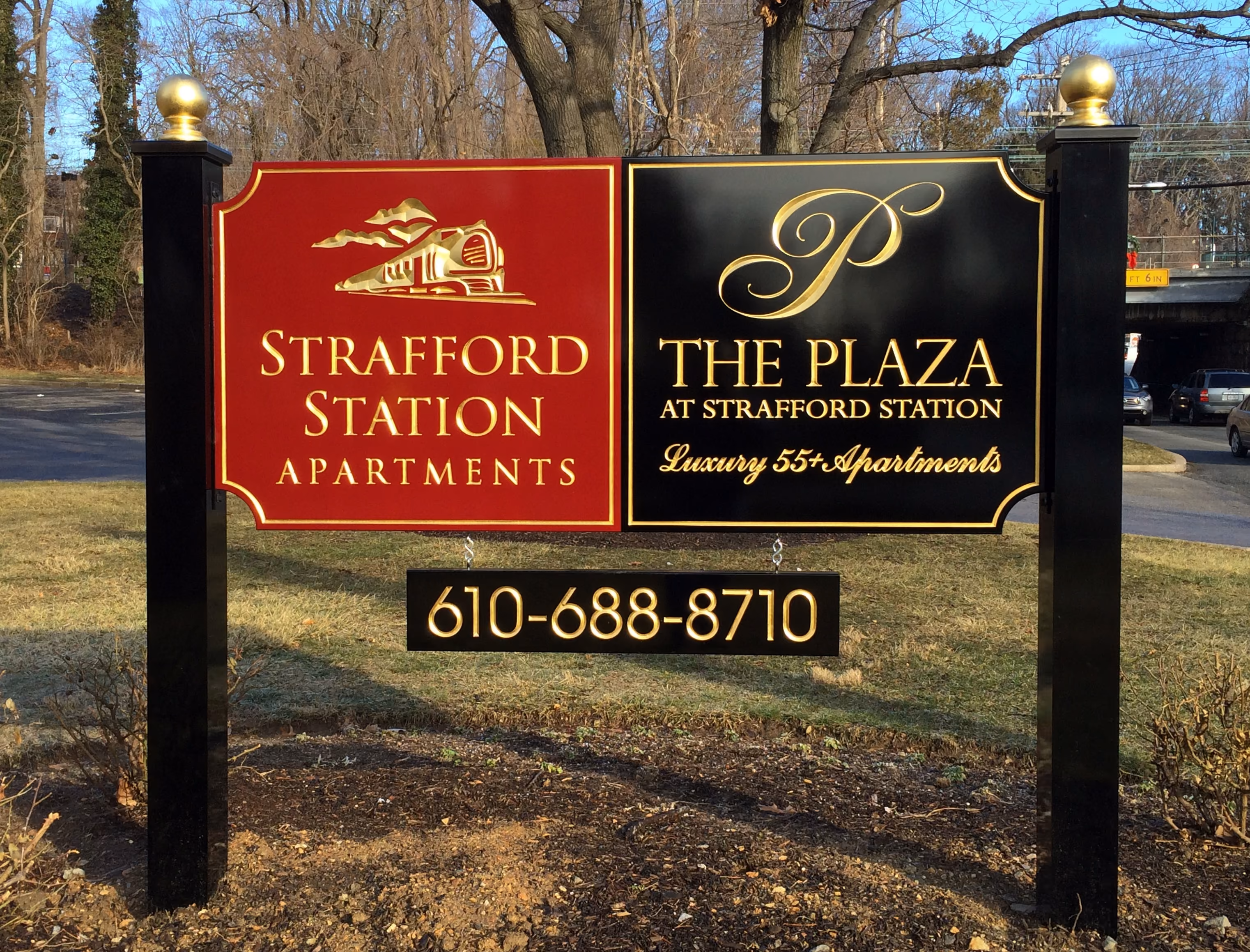 Black, red, and gold carved HDU sign mounted on black posts