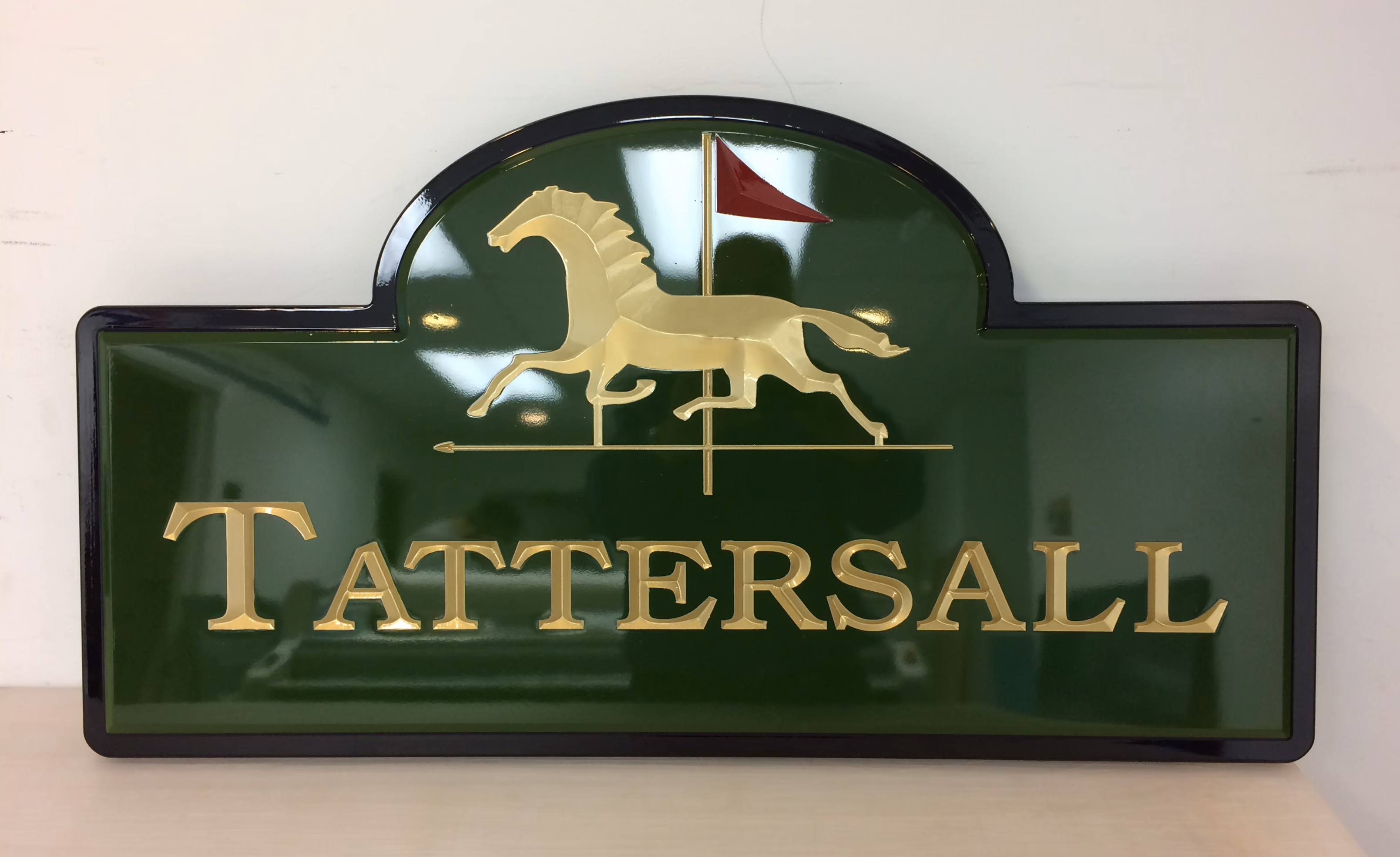 Green, gold, and black carved HDU sign for mounting on a wall
