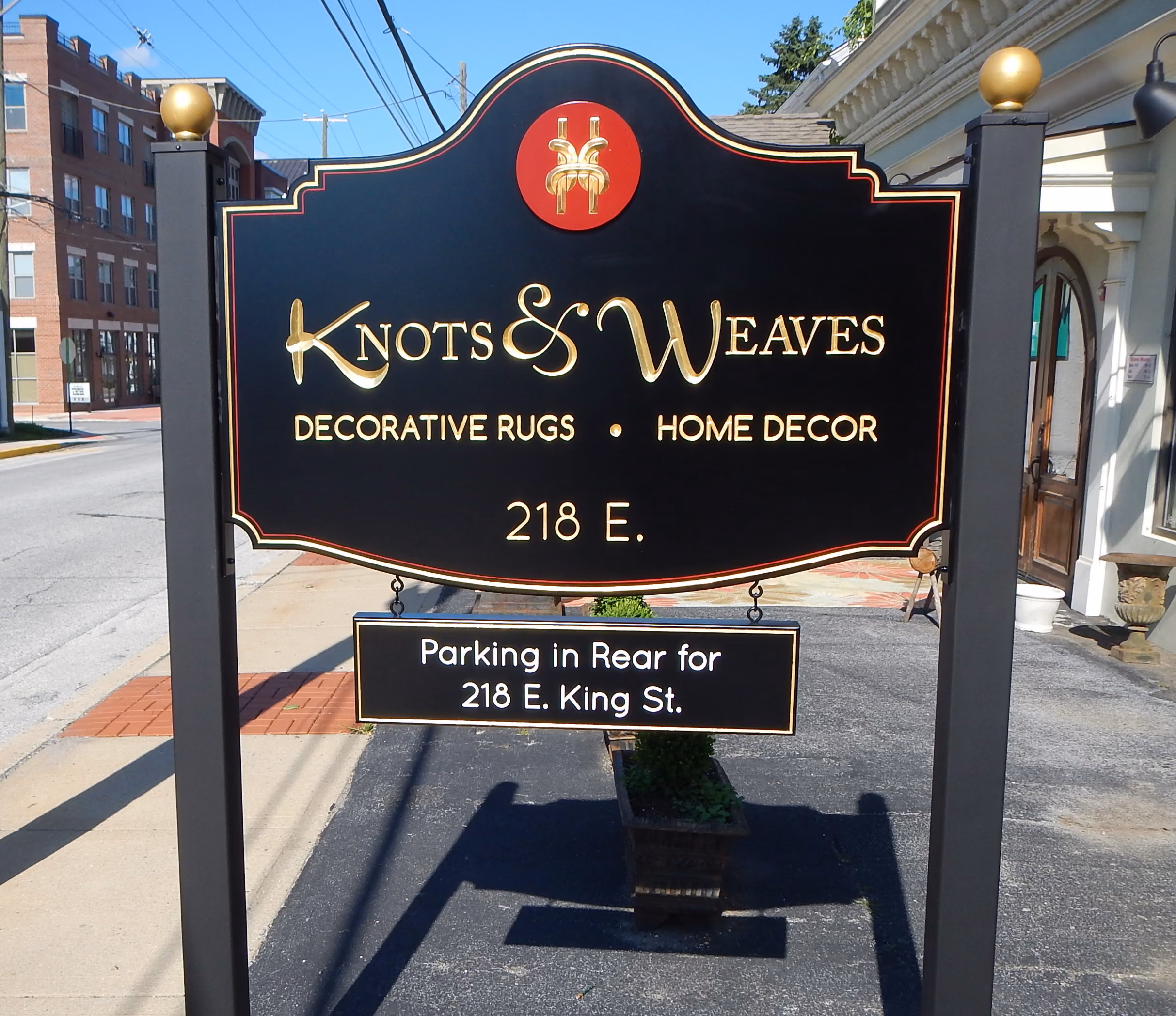 Black, gold, and red carved HDU sign mounted on two black posts