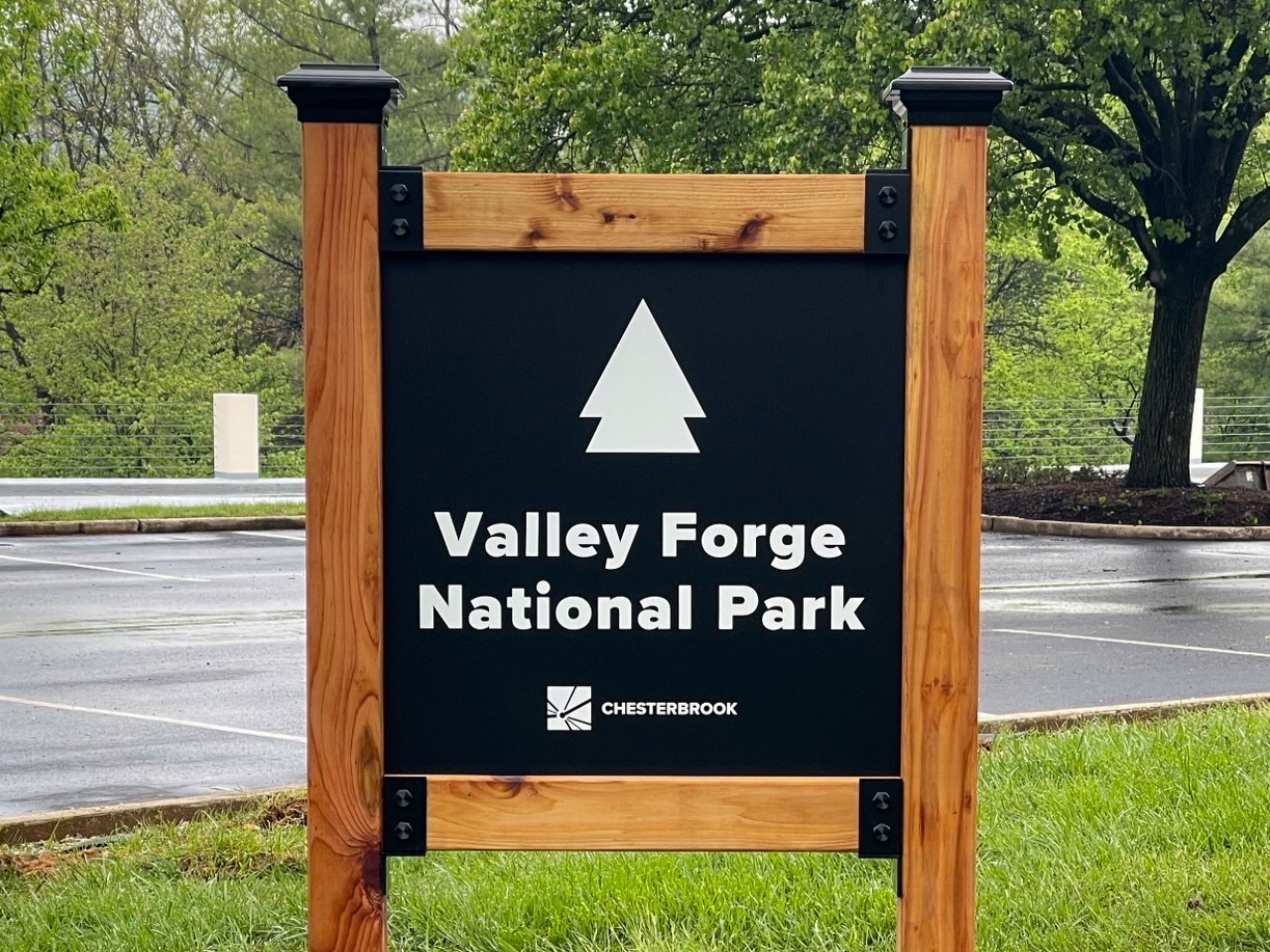 A post and panel sign with wood posts and black and white sign face