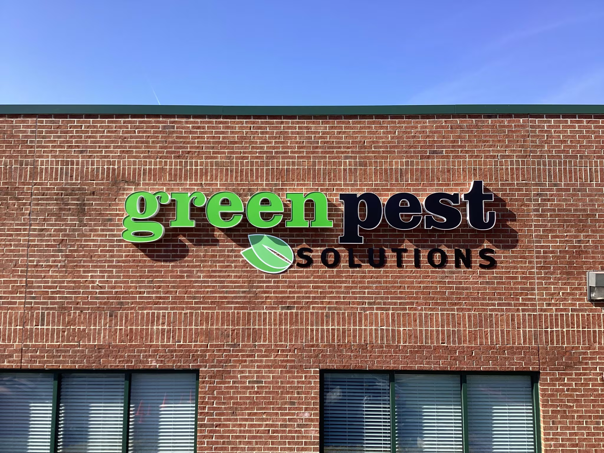 Green and black channel letters mounted high on an exterior brick wall