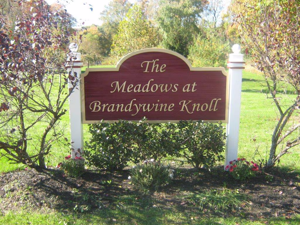 Custom-shaped carved HDU sign mounted on two white posts