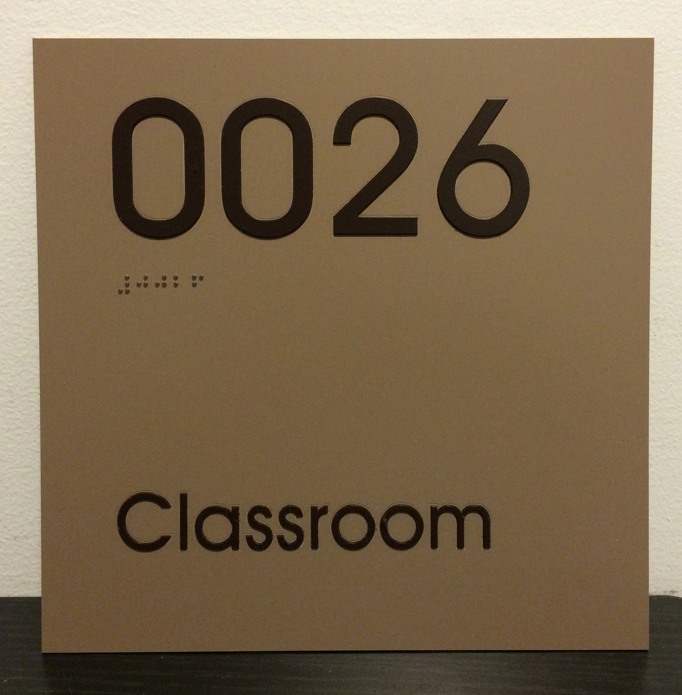 Custom black lettering on a gold-toned ADA sign