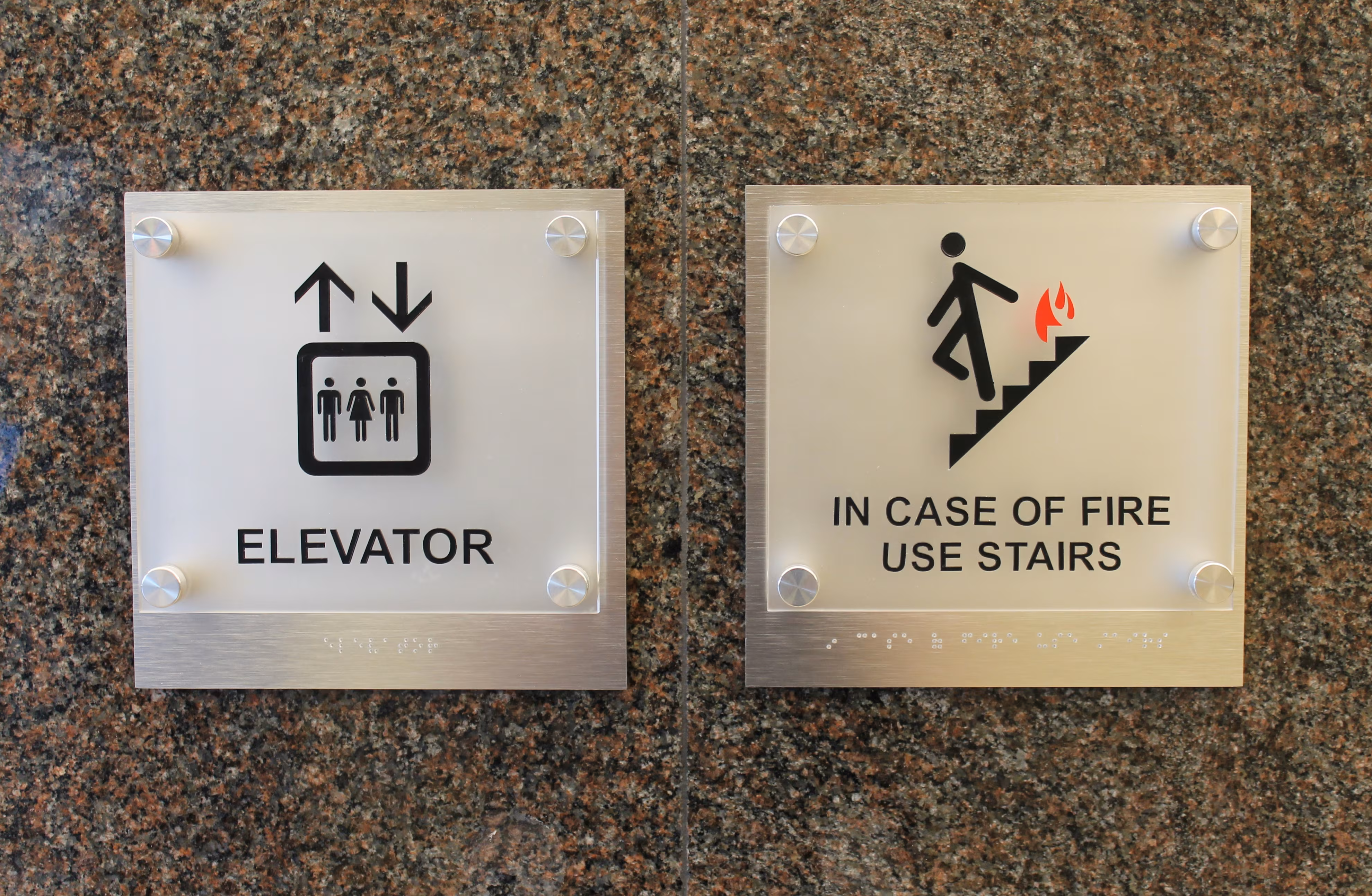 Custom ADA signs made from acrylic panels mounted to brushed aluminum backers with standoffs