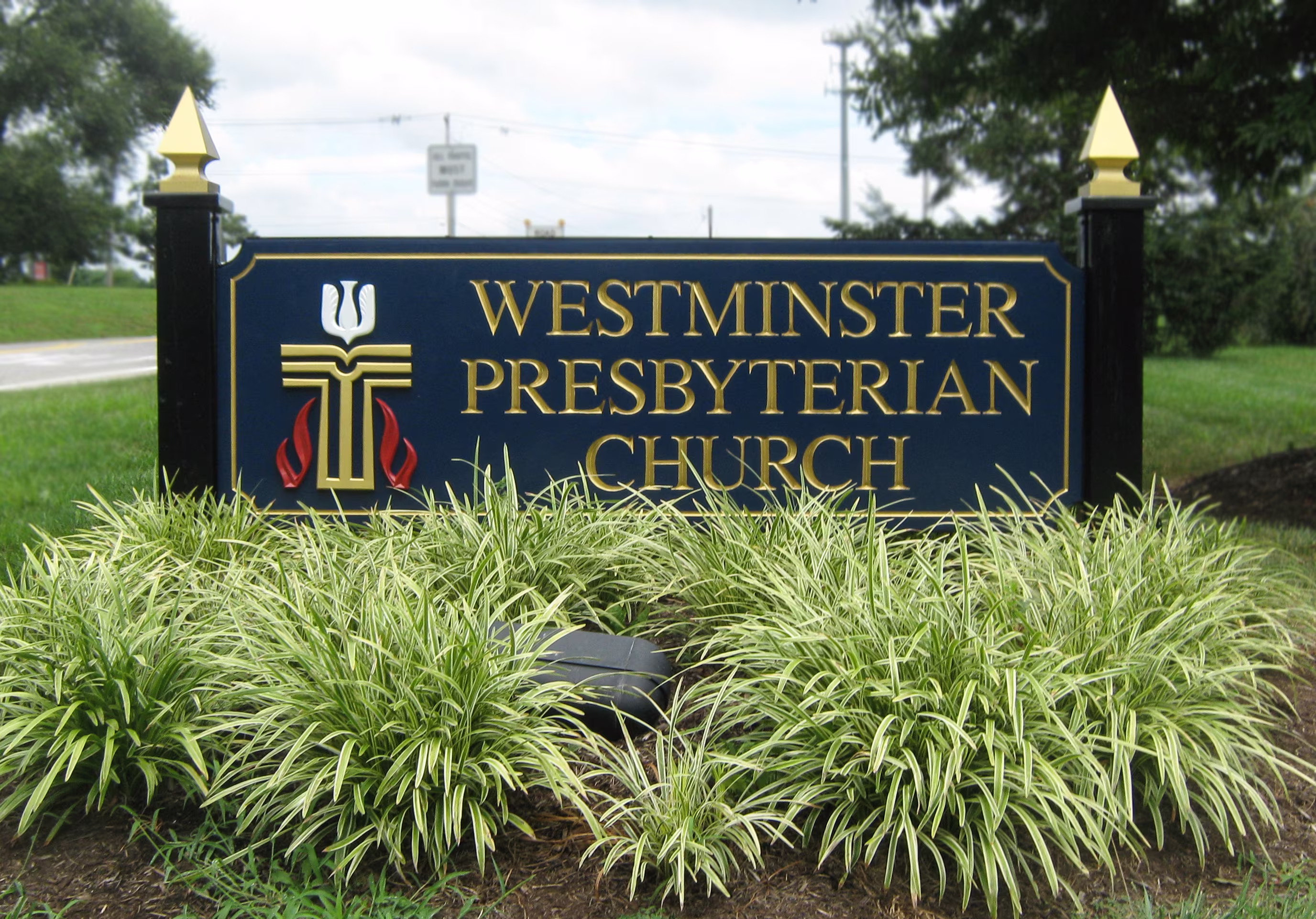 Carved HDU monument sign installed on two black posts with gold finials