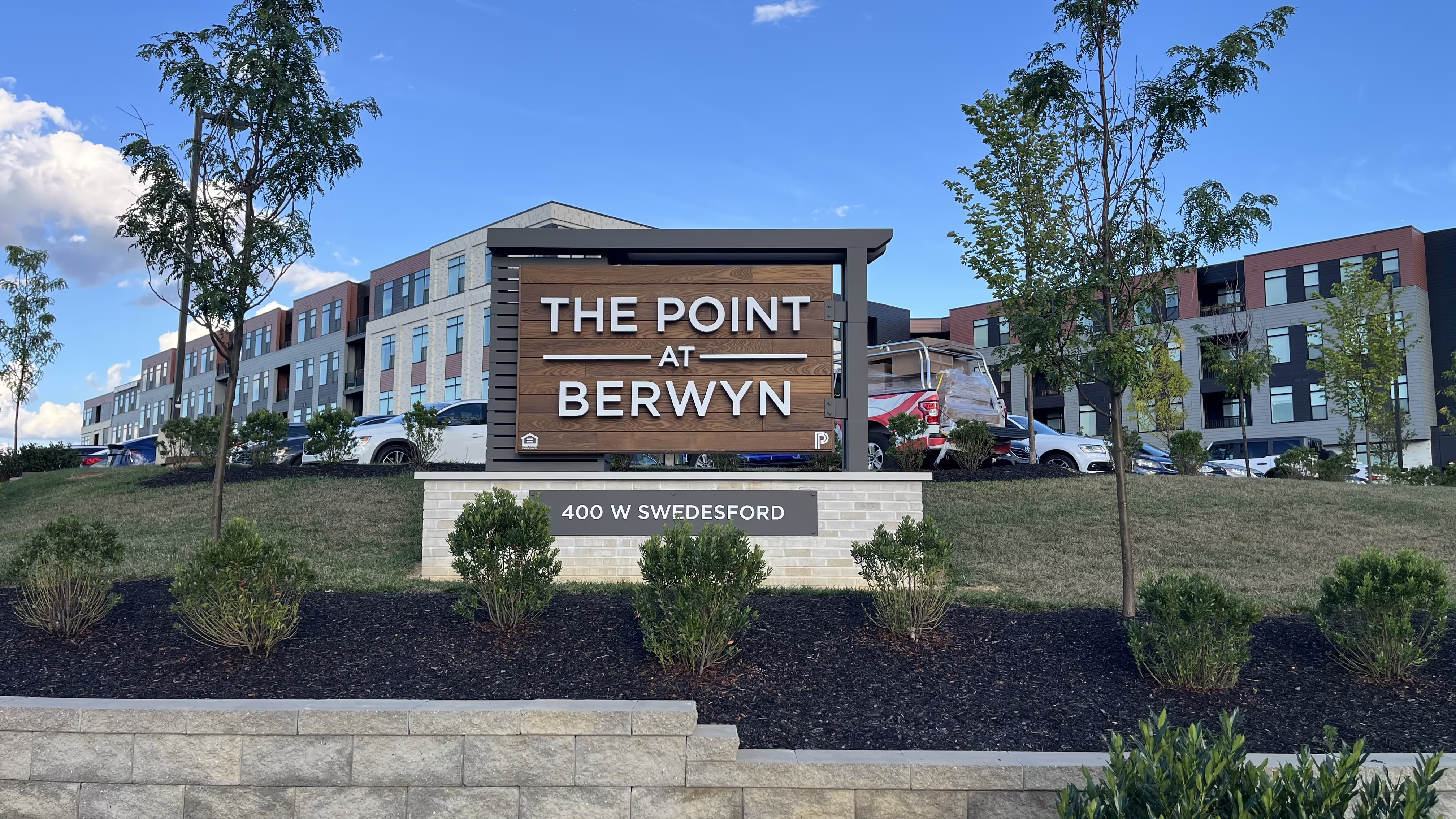 Large monument sign with stained wood paneling and halo-lit channel letters
