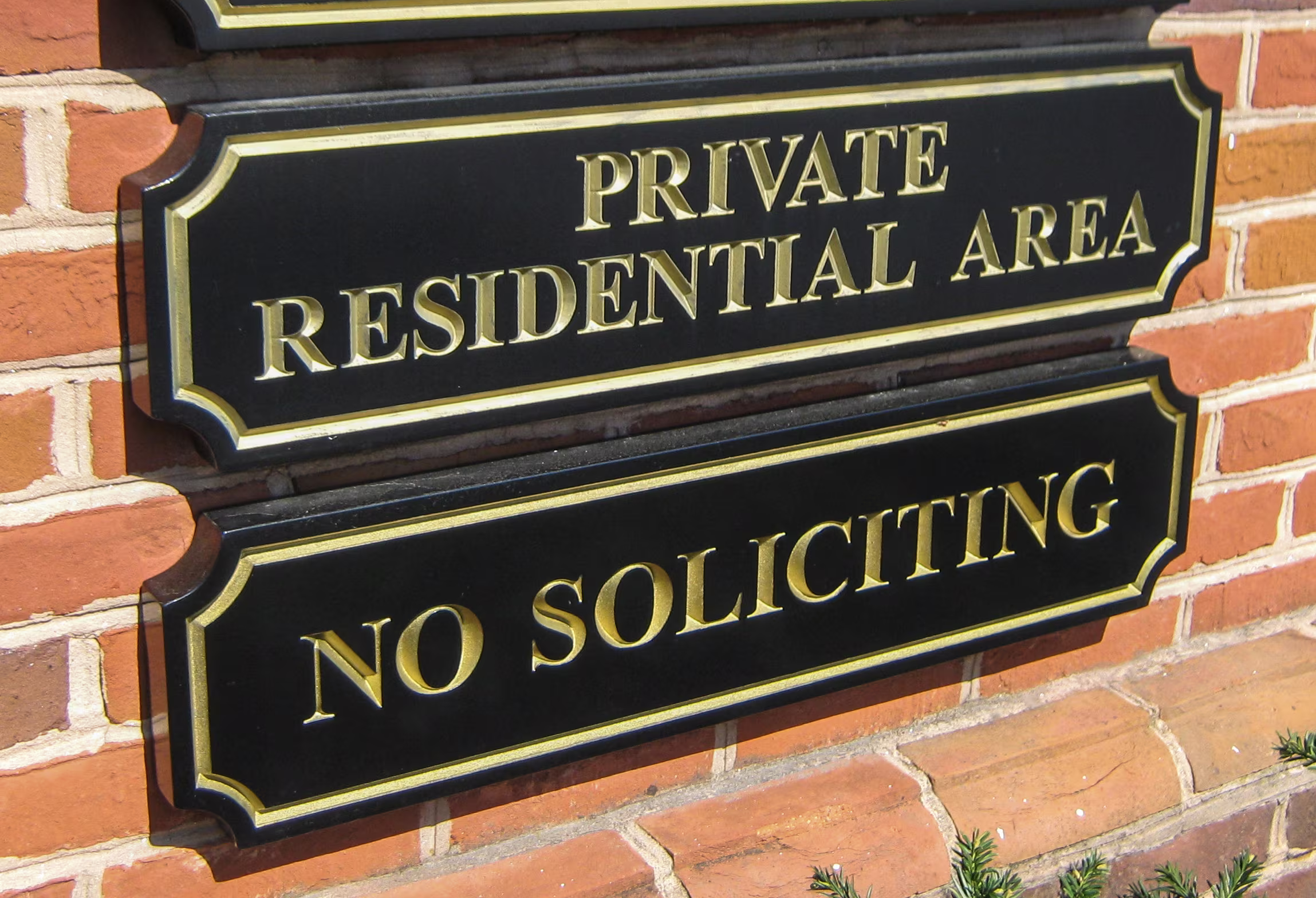 Gold and black carved HDU signs mounted on a brick wall