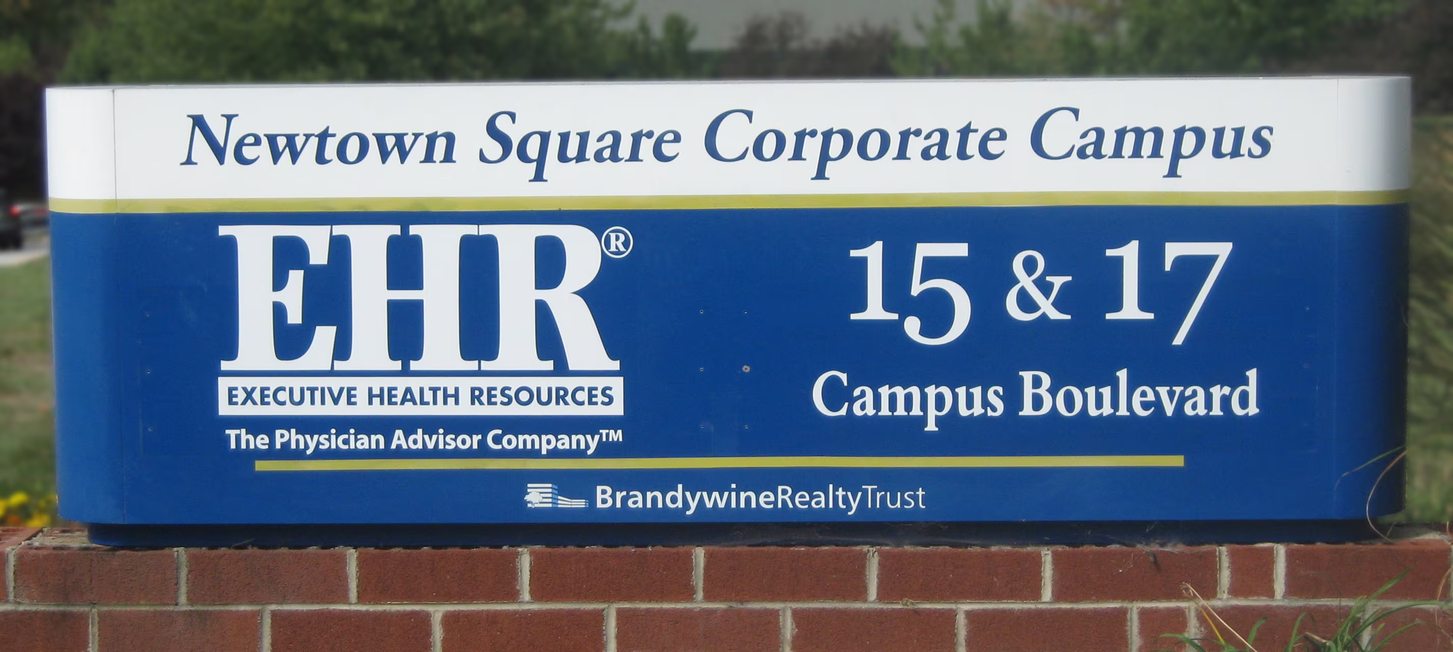 Wide aluminum monument sign atop a brick base