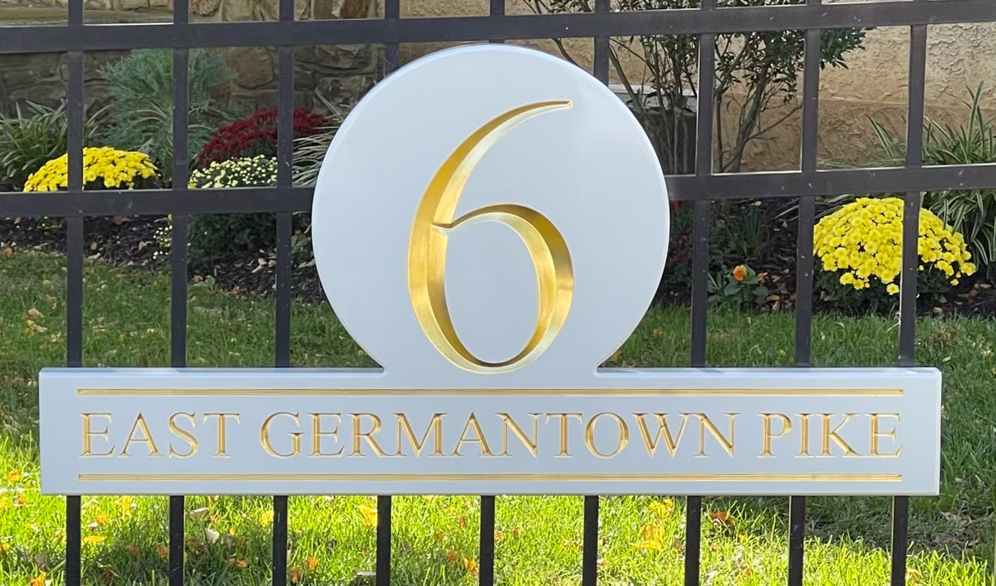 Gold and white carved HDU sign mounted on a black metal fence
