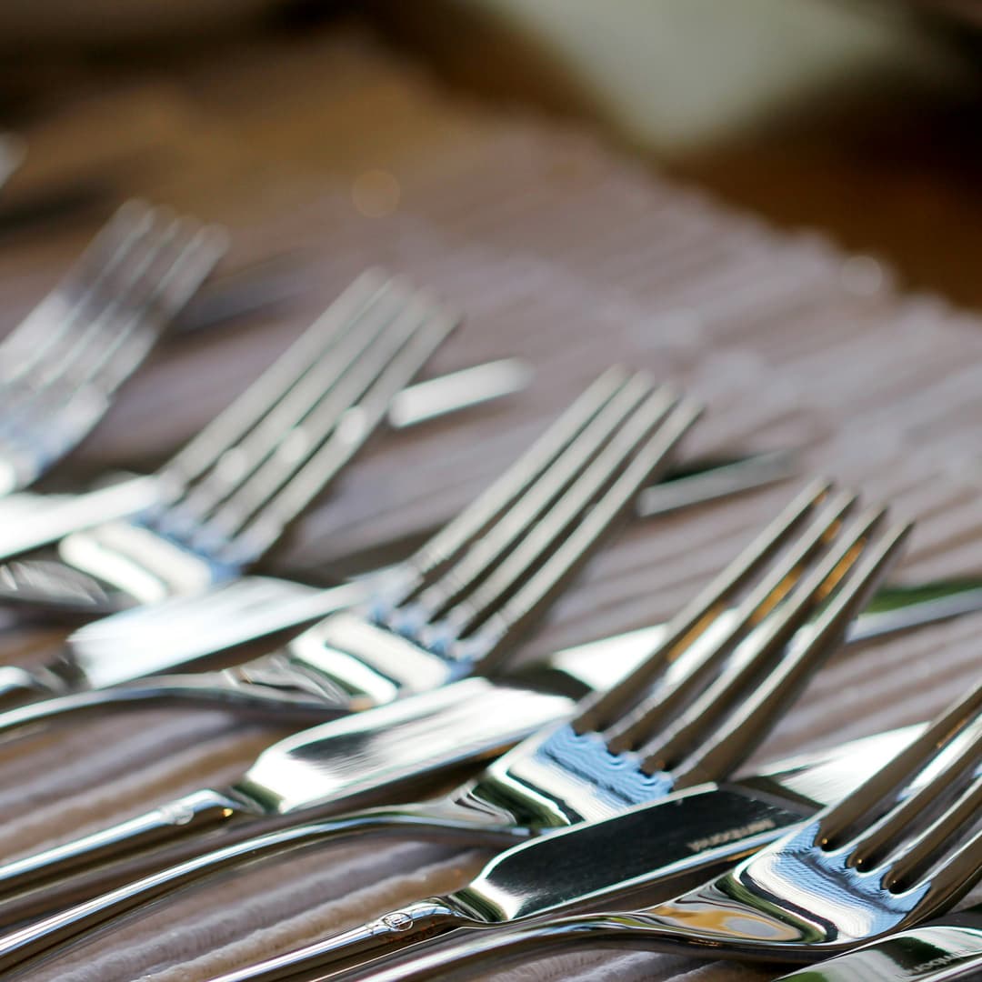 Detailní záběr několika lesklých nerezových vidliček uspořádaných v řadě na povrchu.