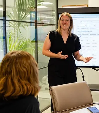 Woman leading a business presentation in a modern office setting.