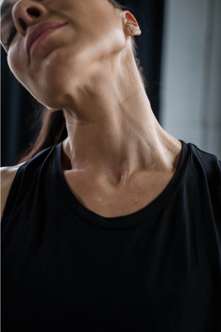 A close-up shot of a woman tilting her head to the side, highlighting her neck and jawline.
