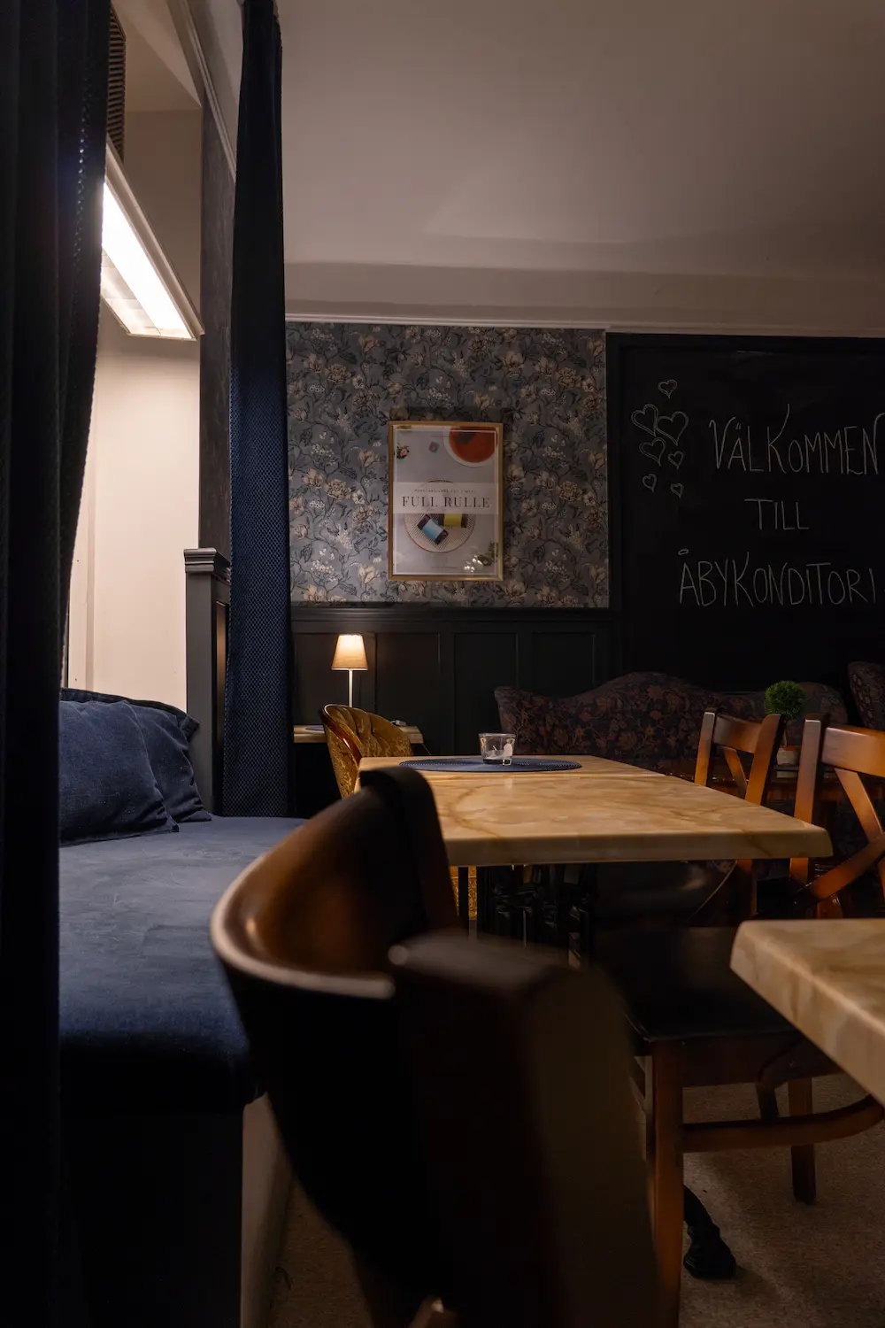 Caféinteriör på Åby Konditori i Åby med sittplatser och välkomstskylt