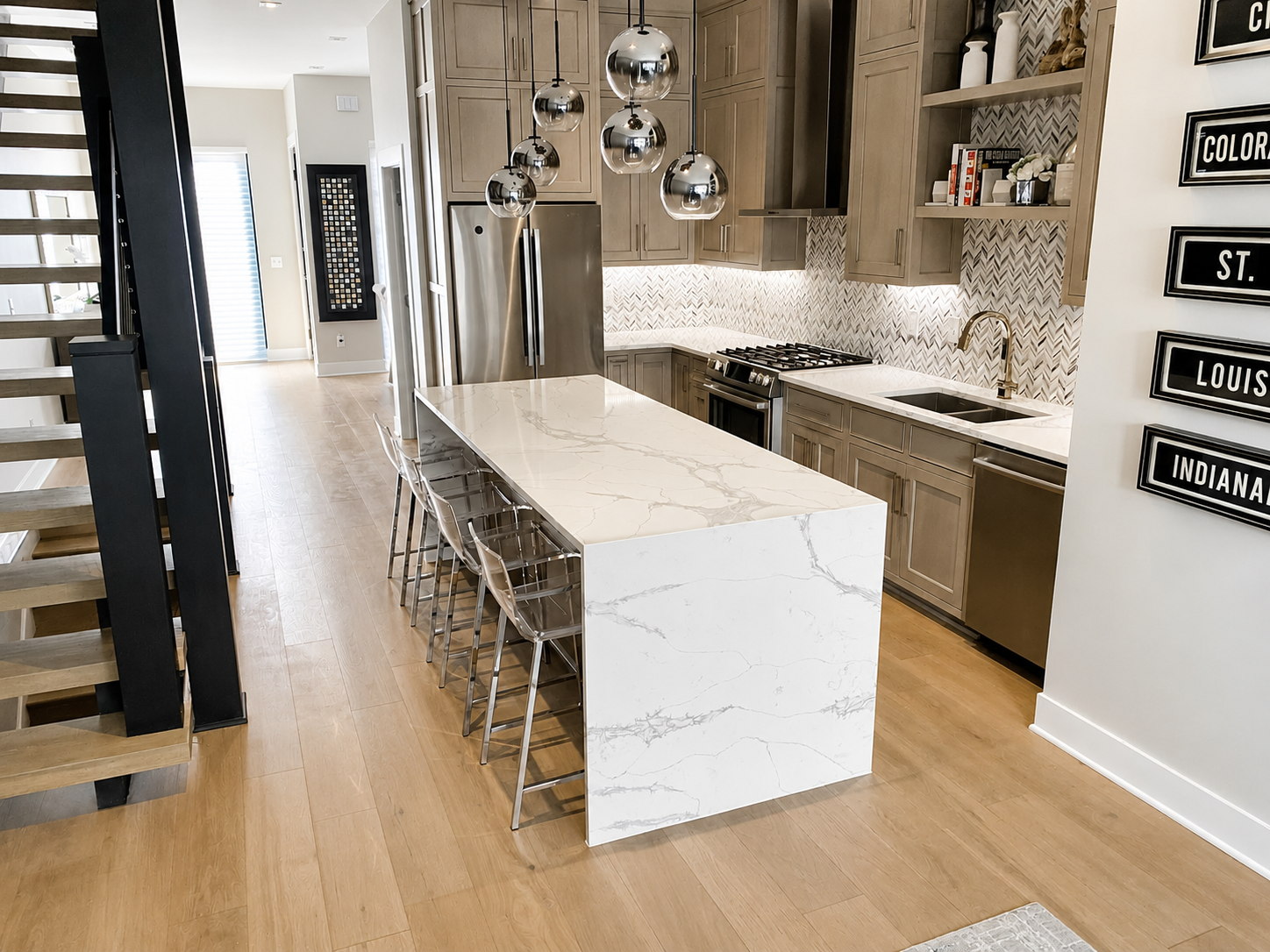 Modern kitchen with waterfall quartz island and open-riser staircase remodeled by JCZ Residential in Indianapolis, Indiana