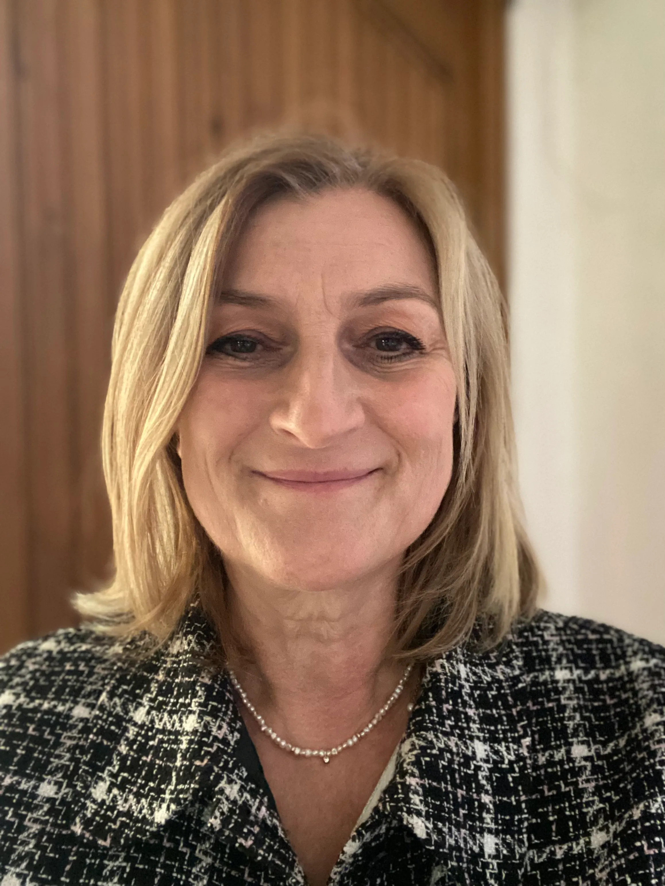 Photo de moi portant des lunettes sur la tête et un blazer noir, souriante devant une porte.