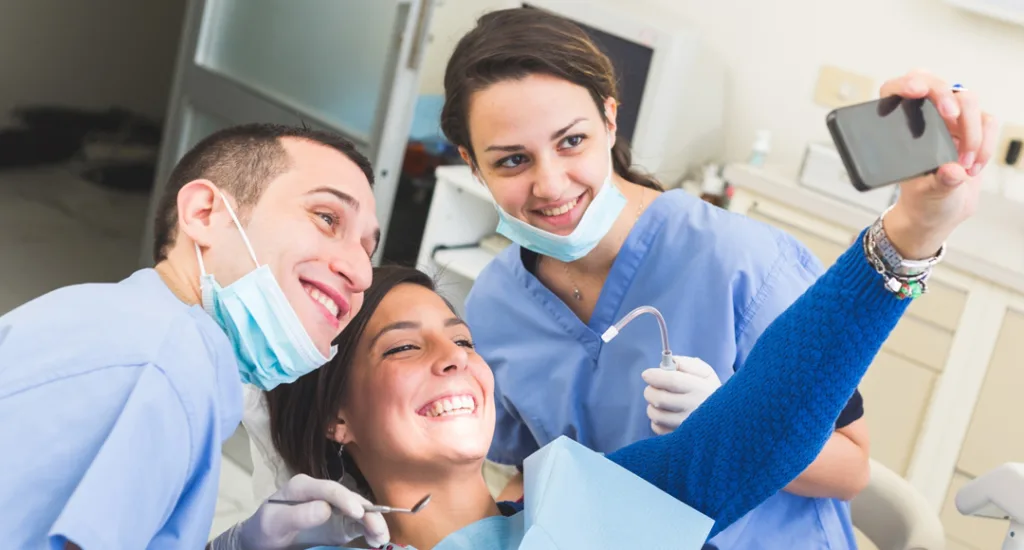 Two dentists taking a selfie with a patient