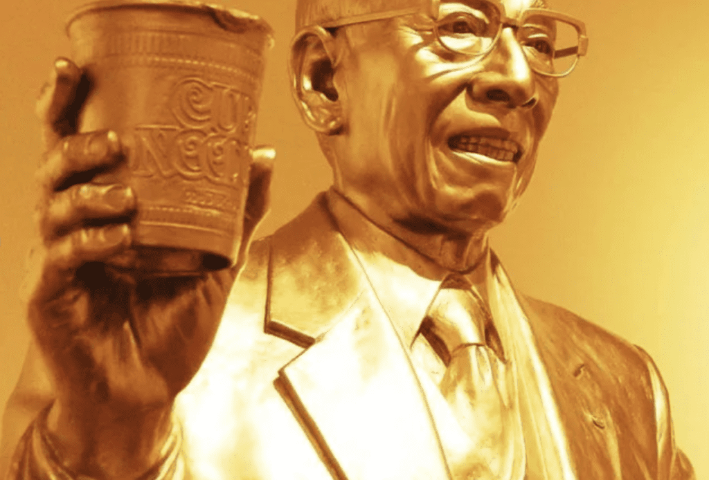 golden statue holding instant noodles cup