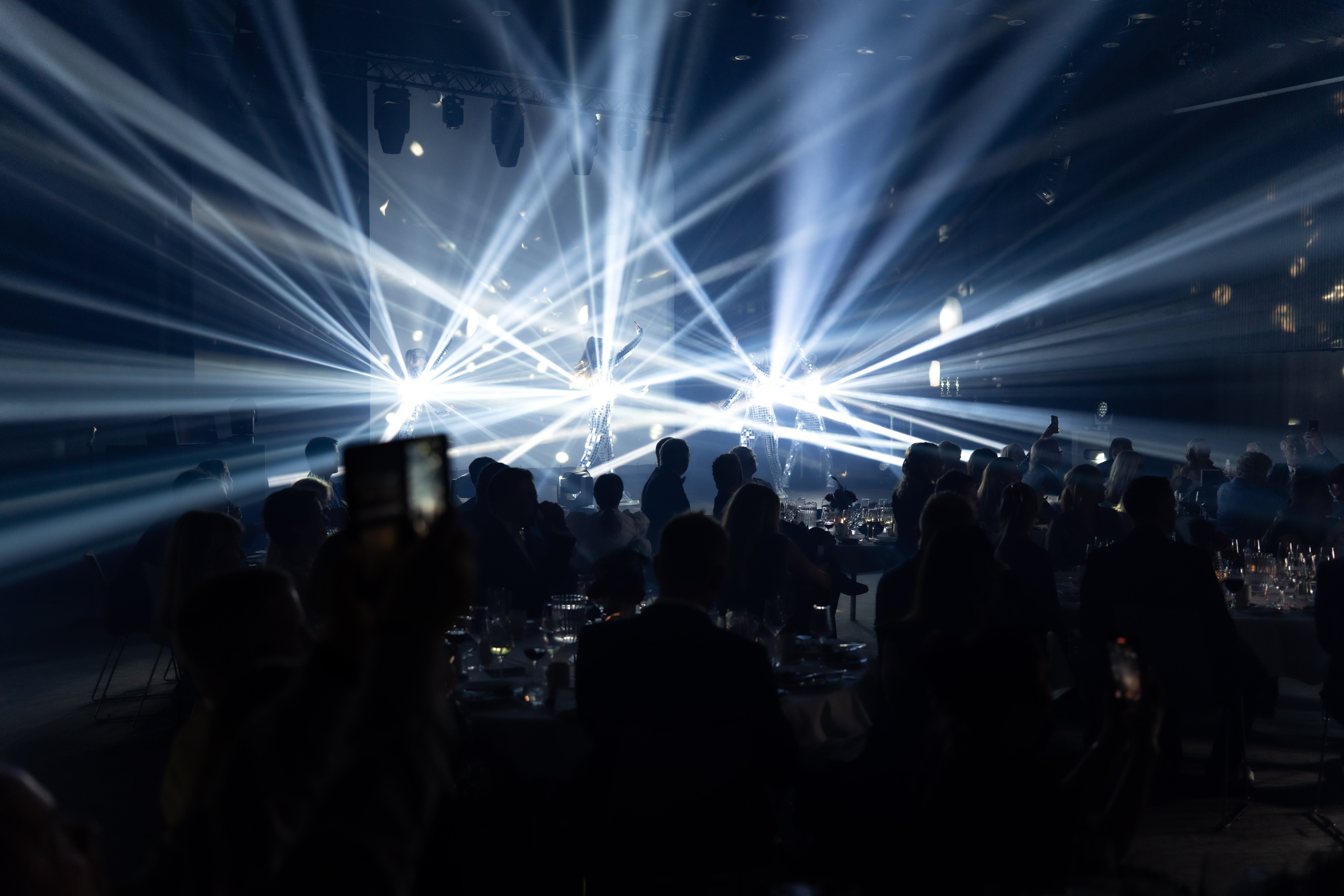 Show de Vida på scenen i drakter dekket med speilglass som reflekterer kraftig lys