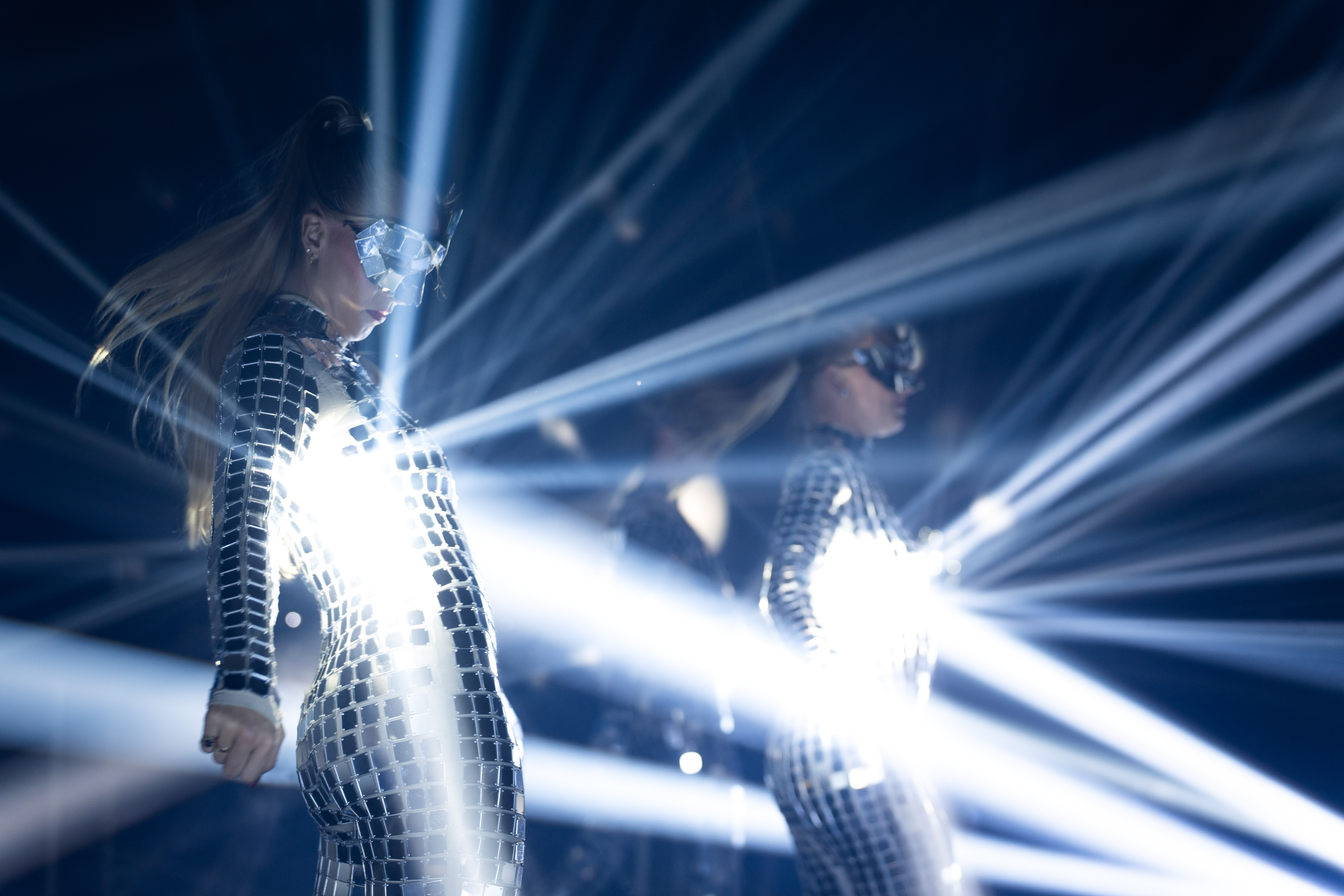 To dansere fra Show de Vida på scenen i drakter dekket med speilglass som reflekterer kraftig lys