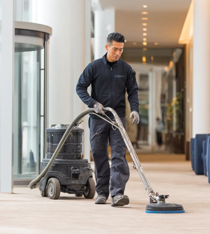 Man using a professional carpet cleaning machine in a hallway with soft lighting.