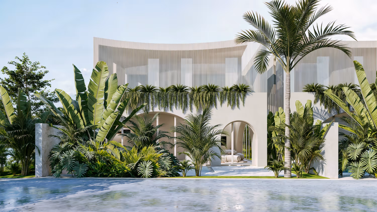 Modern two-story white house with large windows, arched openings, surrounded by abundant tropical plants and palm trees, reflected in a calm water surface in front.