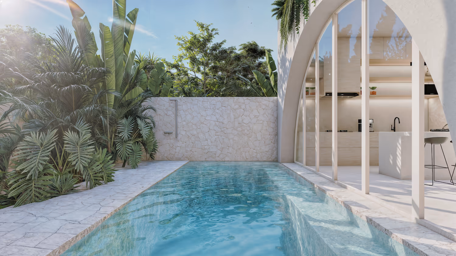 Modern outdoor pool next to a white stone patio with lush tropical plants and a glass-walled kitchen interior.