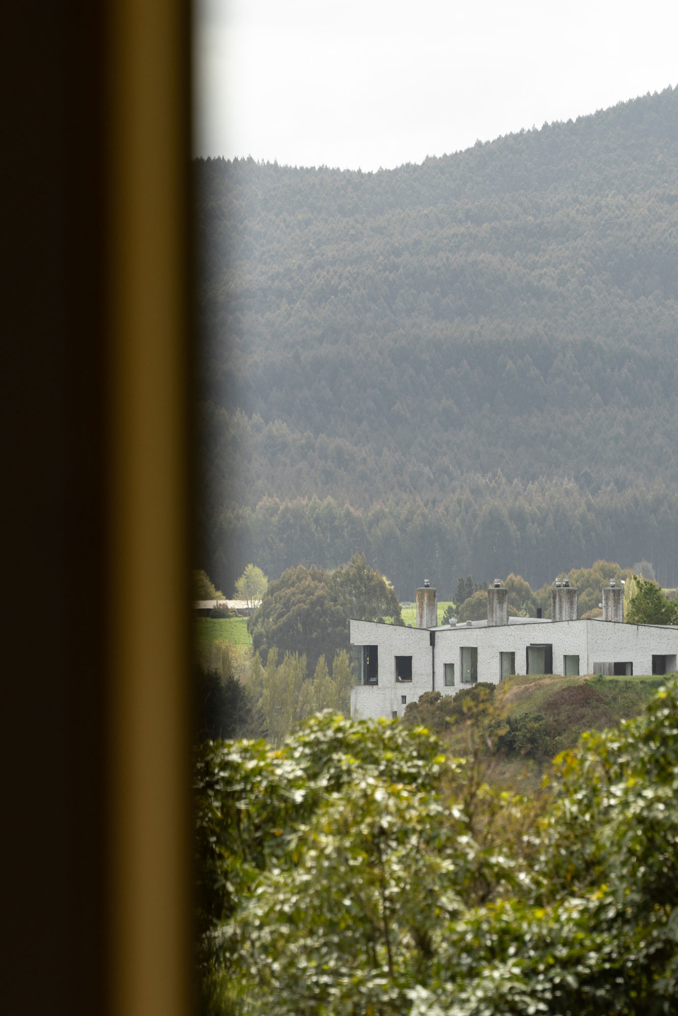 A view through the window of the Courtyard Lakhouse by Object Office towards the Kinloch Lodge in the landscape.