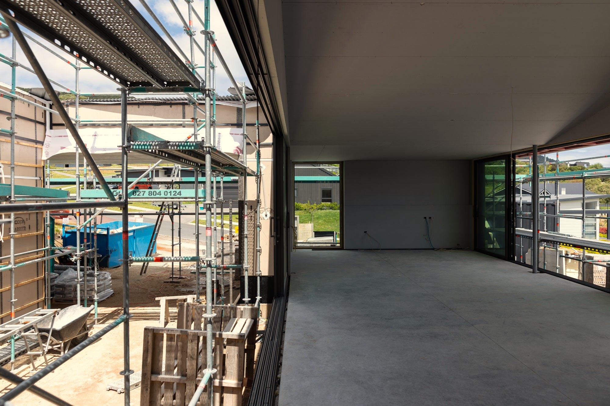 A site photo of the Courtyard Lakehouse under construction in Kinloch shows the interior living and dining spaces next to the outdoor deck.