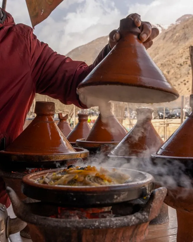 A man standing over a pot filled with food.