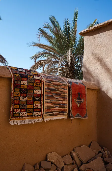 A group of rugs hanging on the side of a building.