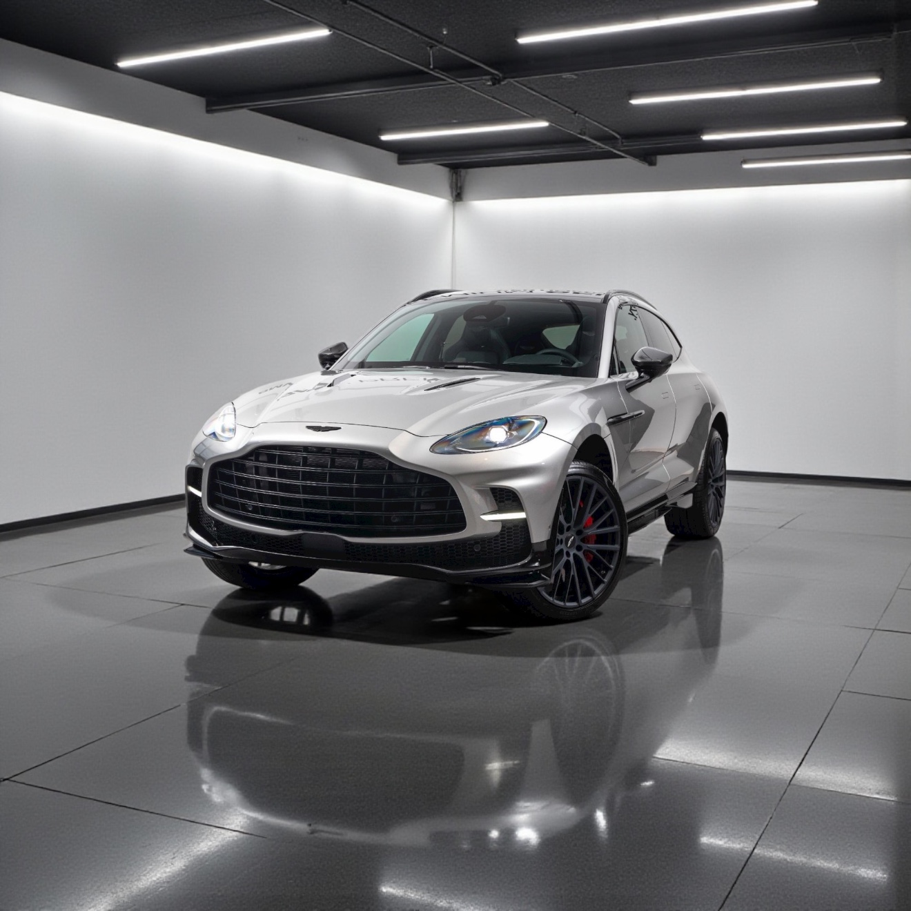Silver luxury sports SUV parked on glossy floor in a modern white-walled room with black ceiling and LED strip lights.