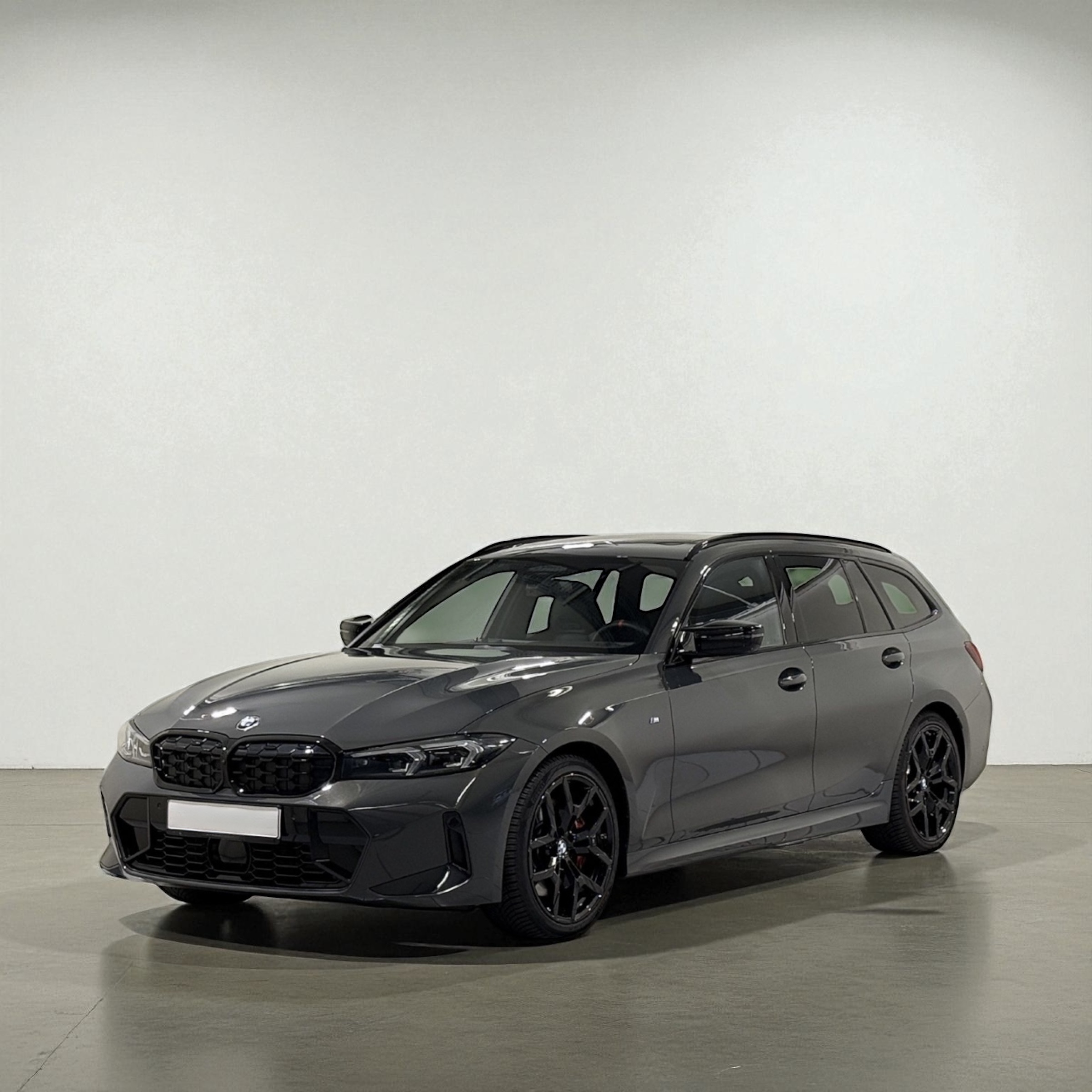 Dark gray BMW wagon parked indoors on a polished concrete floor against a plain light wall.