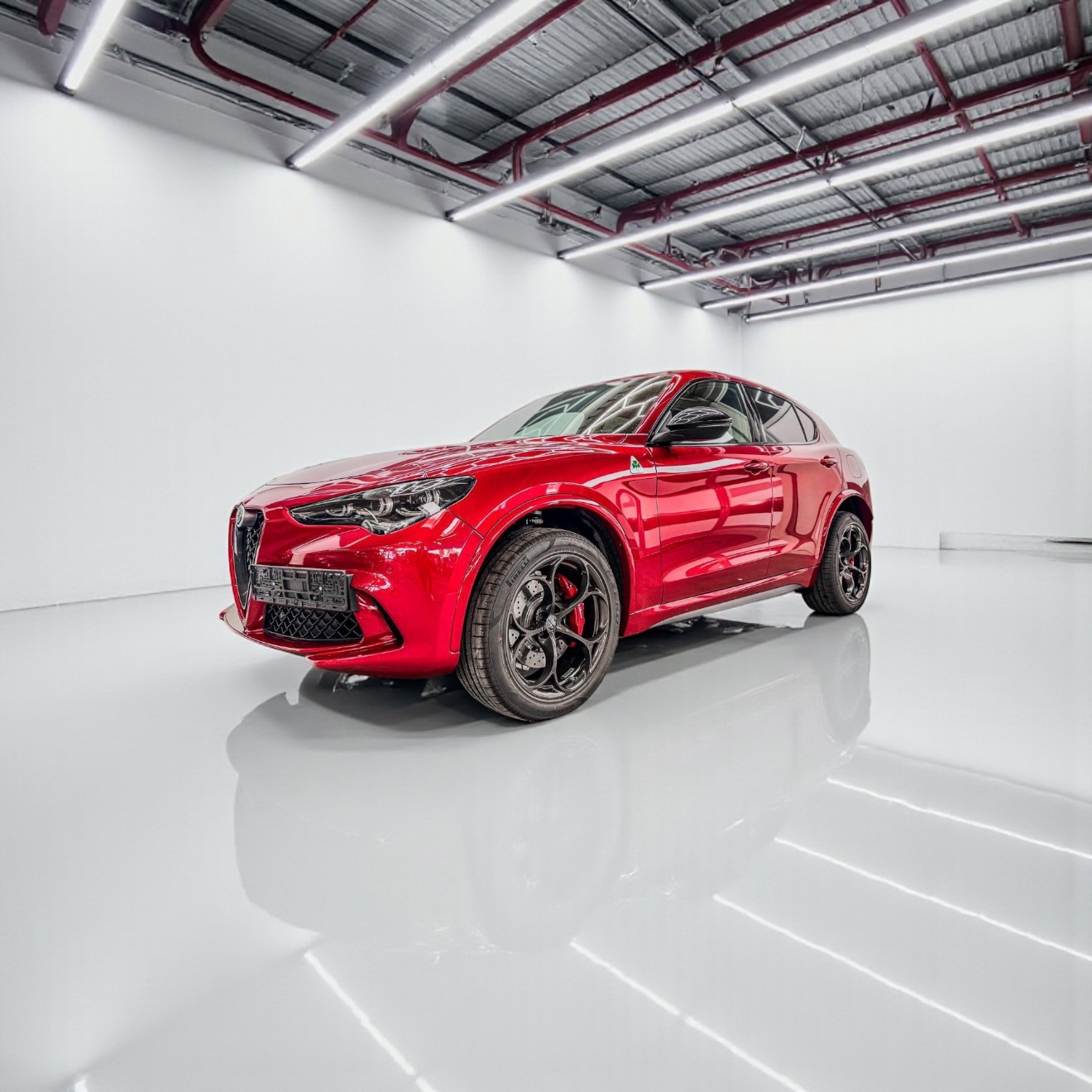 Red Alfa Romeo Stelvio SUV parked in a bright, minimalist white showroom with reflective flooring.
