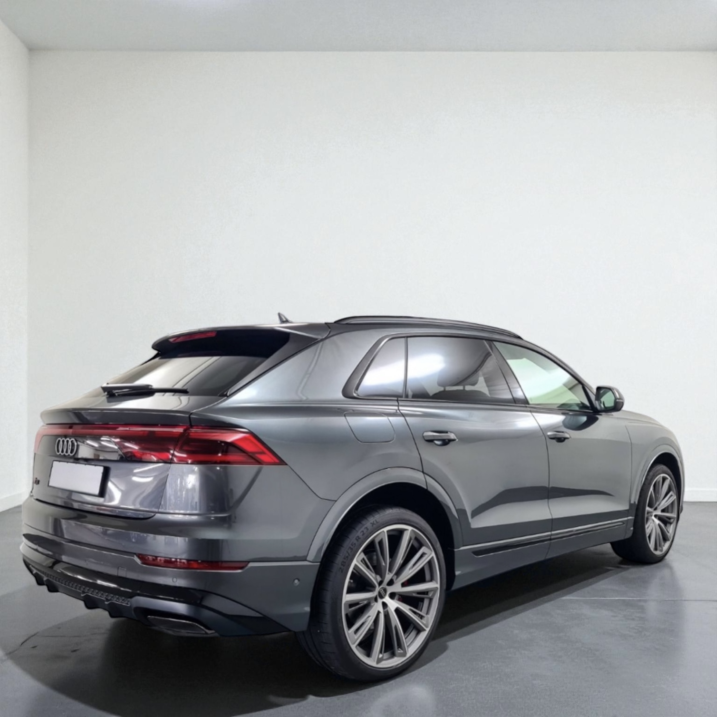 Gray Audi SUV parked indoors on a gray floor with tinted windows and modern taillights.