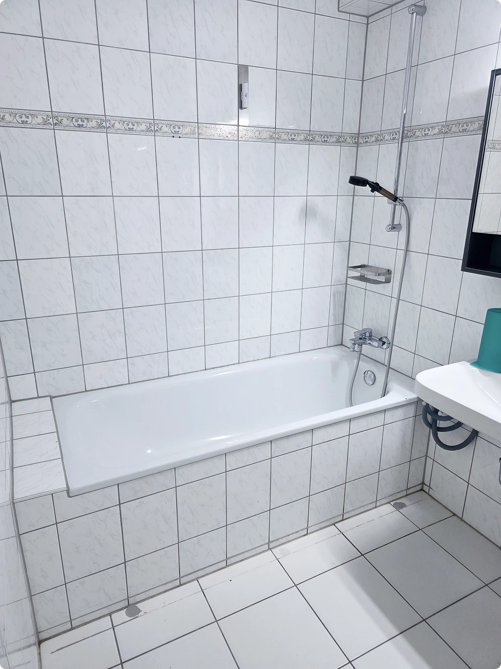 Bad mit normaler Badewanne, glatten und rutschigen Fliesen sowie ohne Haltegriffe oder barrierefreie Ausstattung.