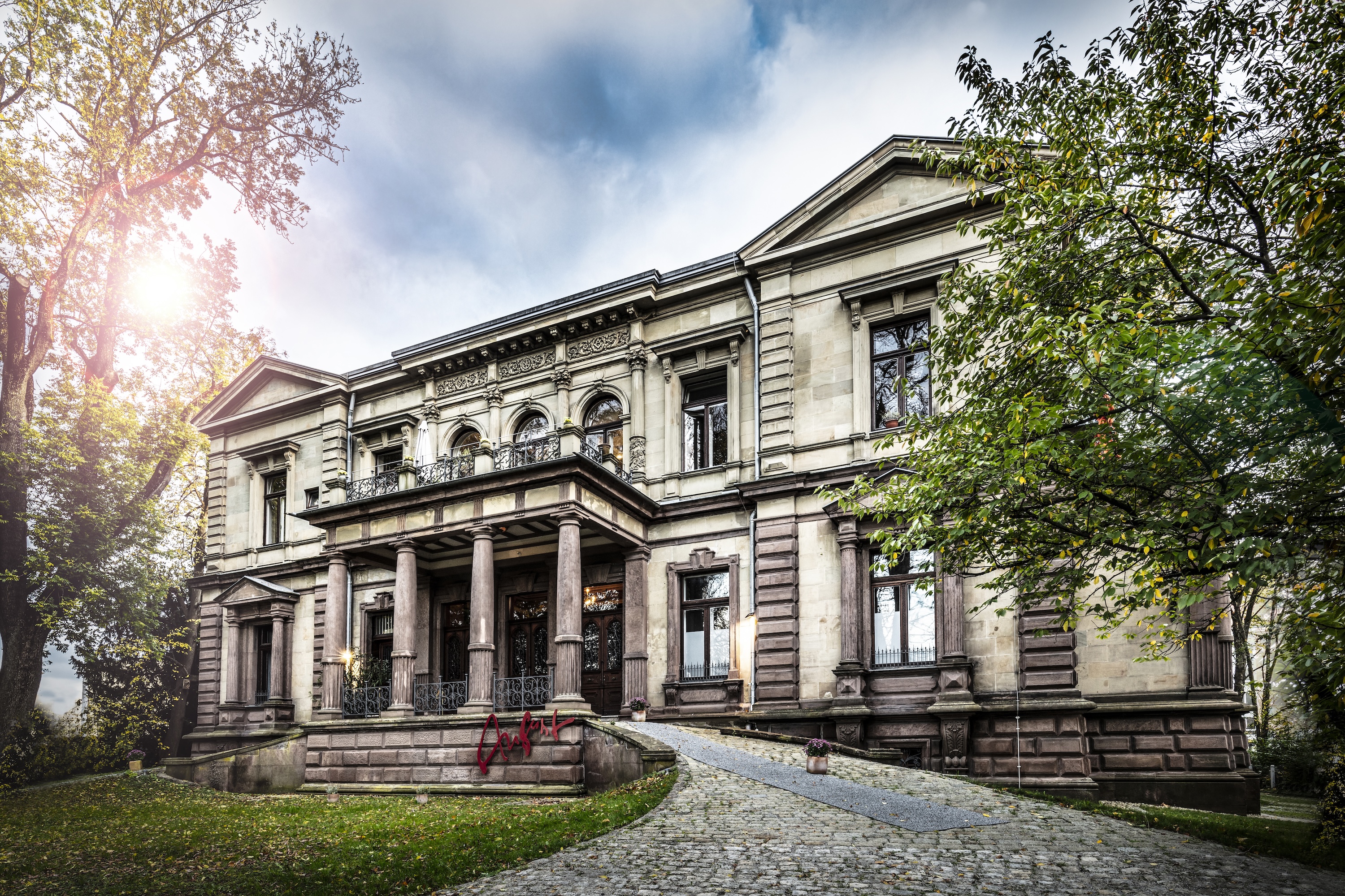 Standort Villa Haag: Historisches Gebäude mit klassizistischer Fassade, umgeben von gepflegtem Garten.
