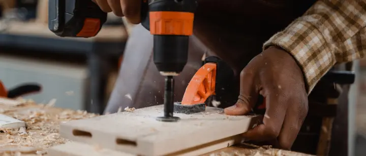 a drill and wood held by a carpenter