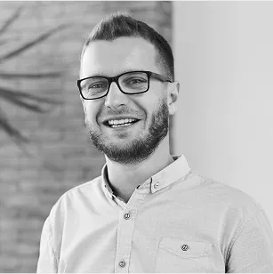 Black and white photo of a young man smiling wearing eyeglasses