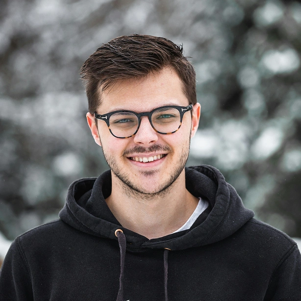 Young man wearing eyeglasses in front of the winterlandscape