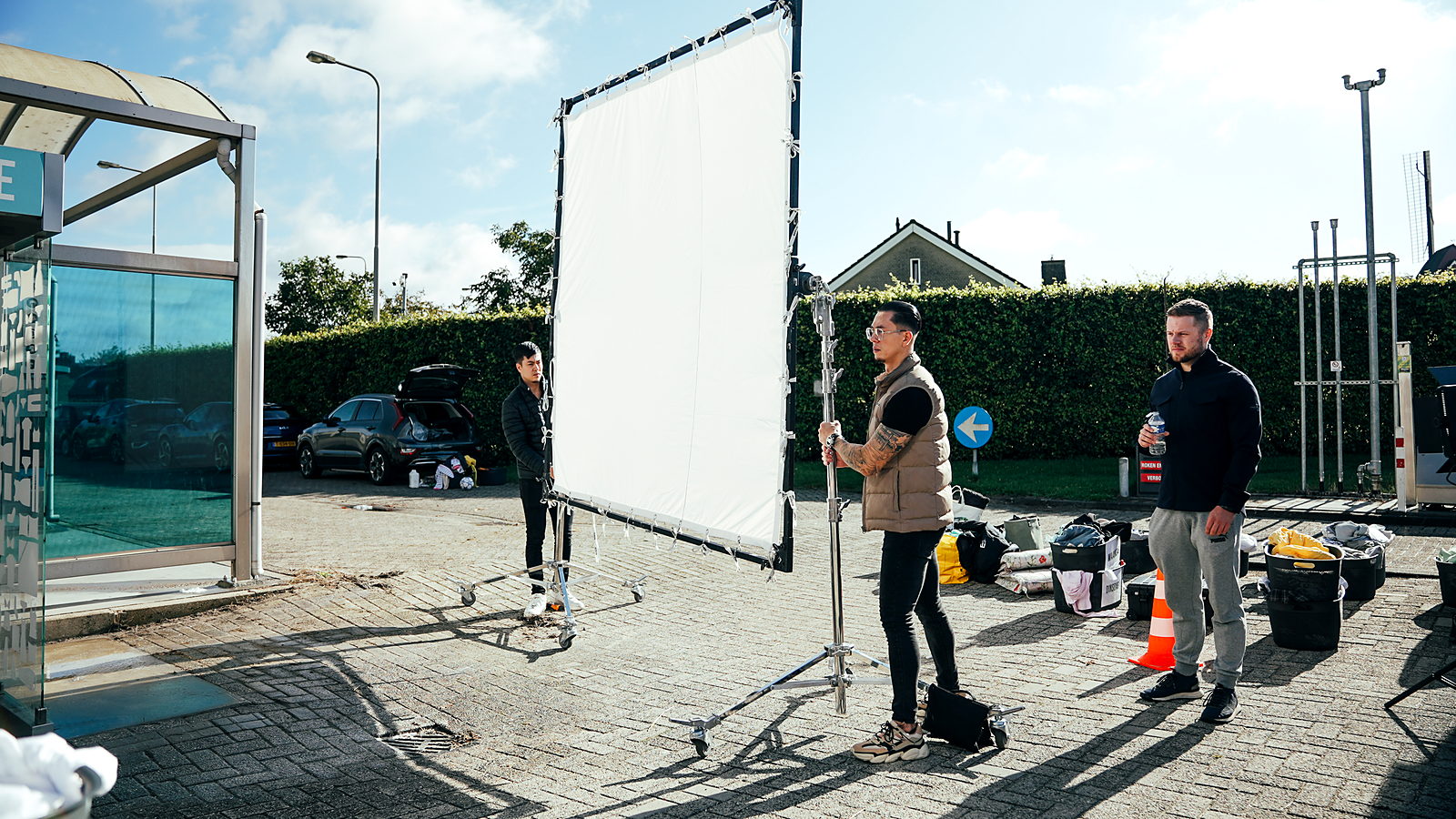 Crewleden bouwen een groot diffusieframe op tijdens een videoproductie op locatie