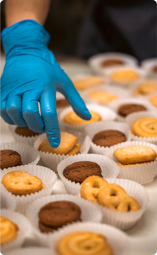 a hand in a glove inspecting cookies