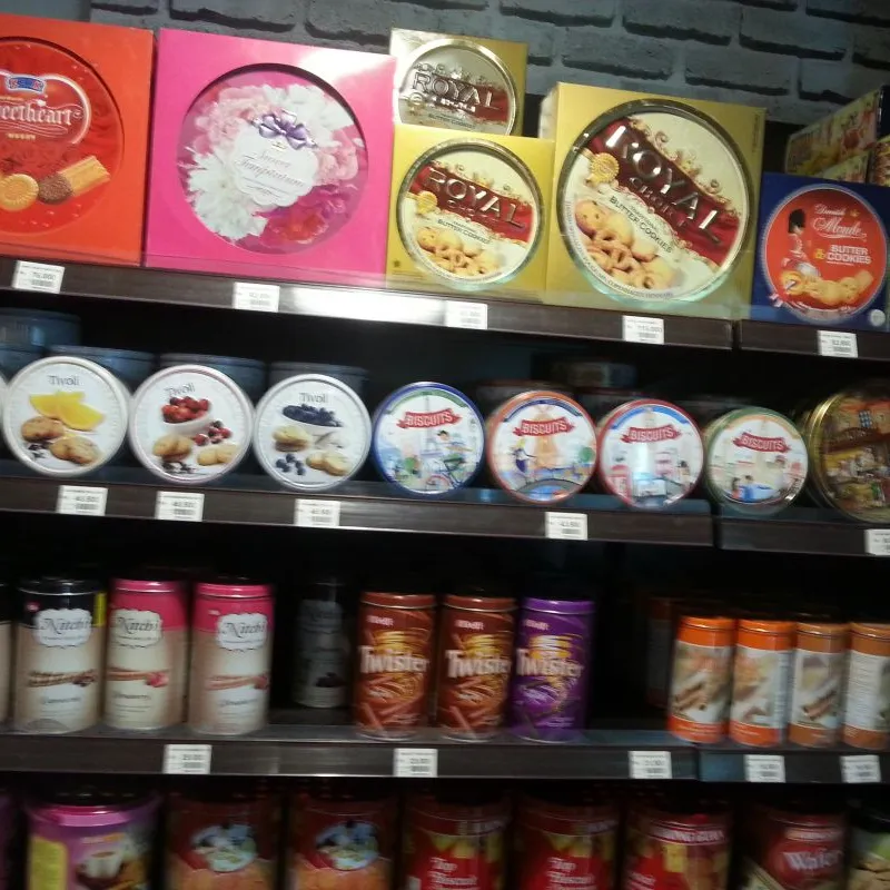 Shelves of round cookie tins and gift boxes in an Indonesian supermarket