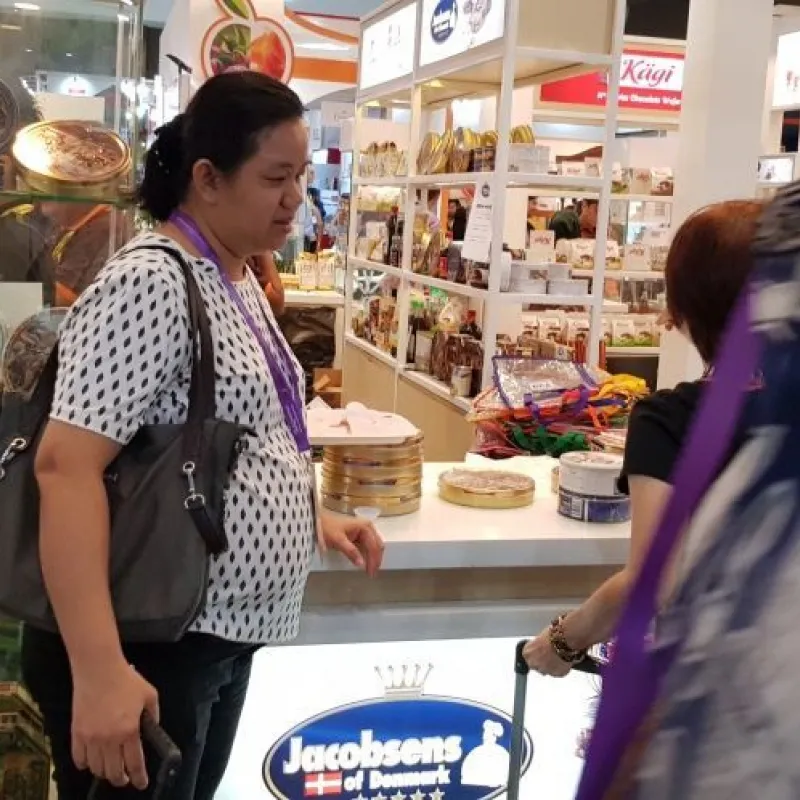 Woman shopping at a Jacobsens of Denmark cookie counter in Indonesia