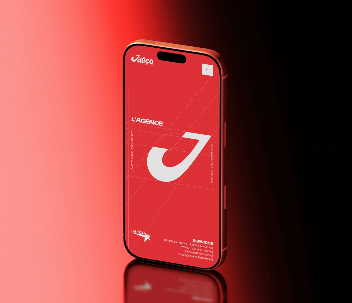 Smartphone affichant le logo de l’agence Jaéco sur un fond rouge, illustrant son identité visuelle et sa présence digitale.