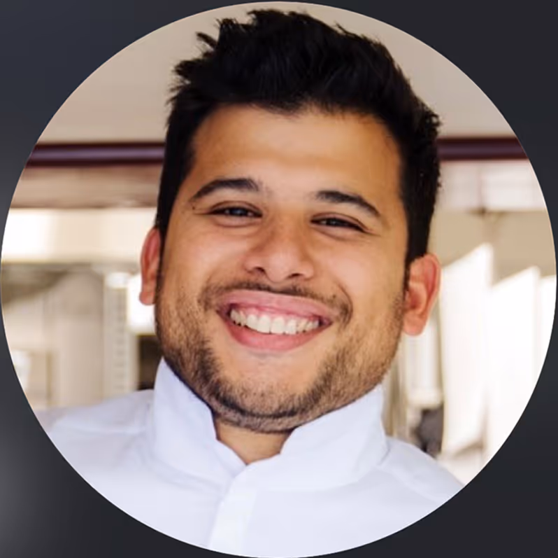 Homme souriant portant une chemise blanche, en intérieur.