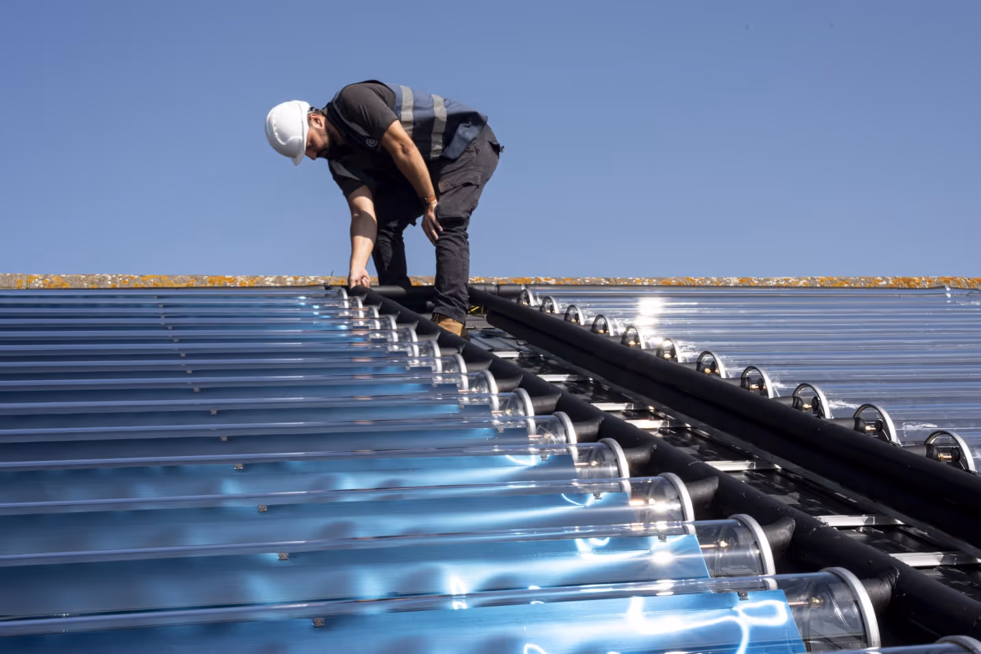 Worker installing Virtu solar thermal collectors on pitched roof.