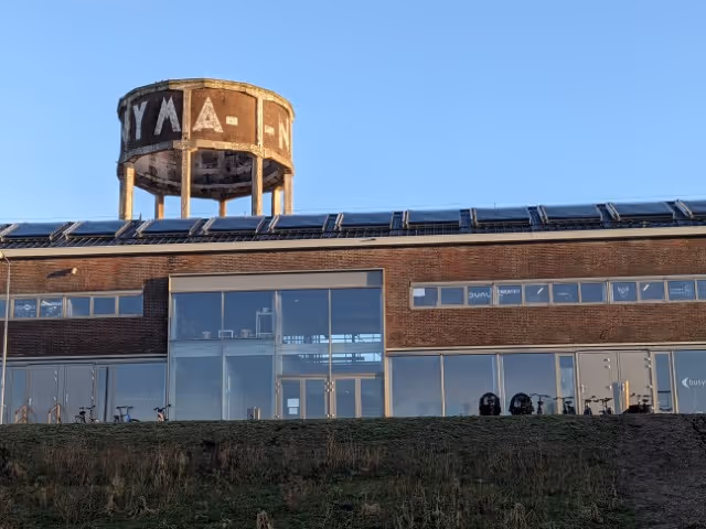 Industrial building with solar thermal collectors on. With blue sky.